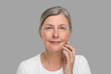 Photo of Portrait of senior woman with aging skin on grey background. Rejuvenation treatment