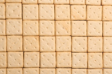 Many delicious crackers as background, top view