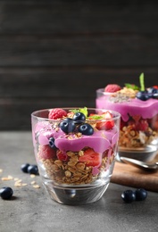 Tasty dessert with acai smoothie, granola and berries on grey table