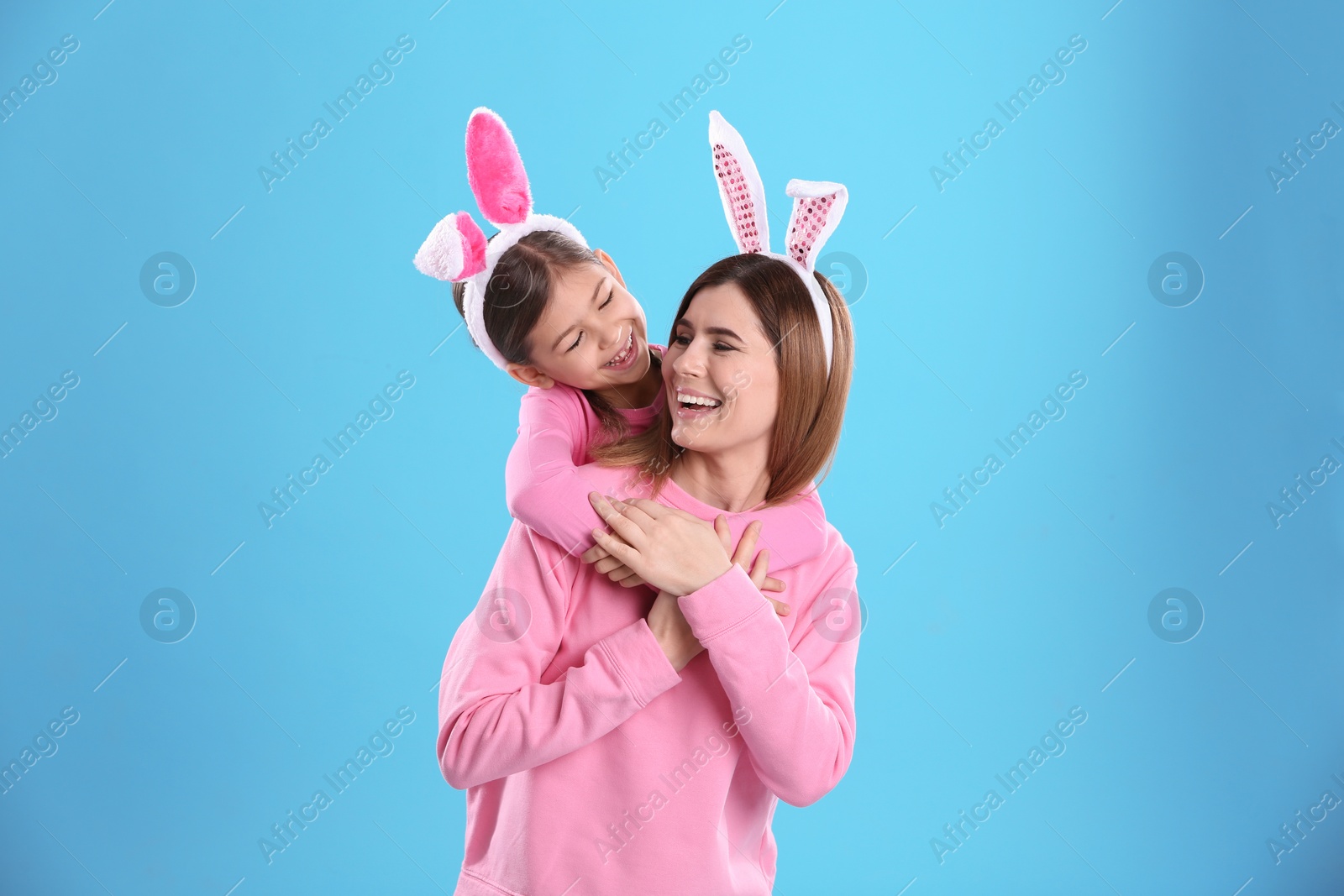 Photo of Happy woman and daughter with bunny ears on color background