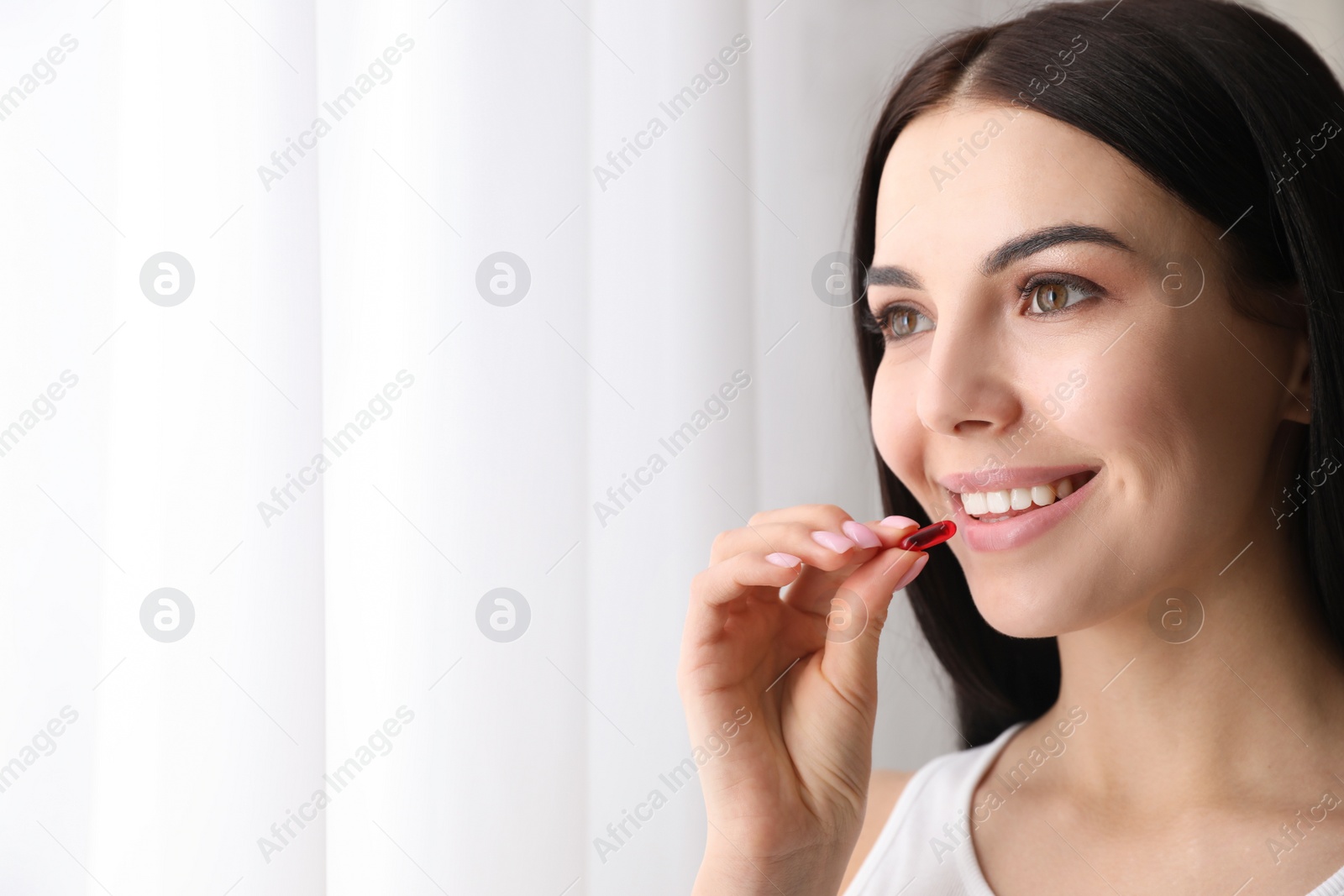Photo of Woman taking vitamin capsule indoors. Space for text
