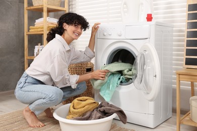 Woman taking laundry out of washing machine indoors