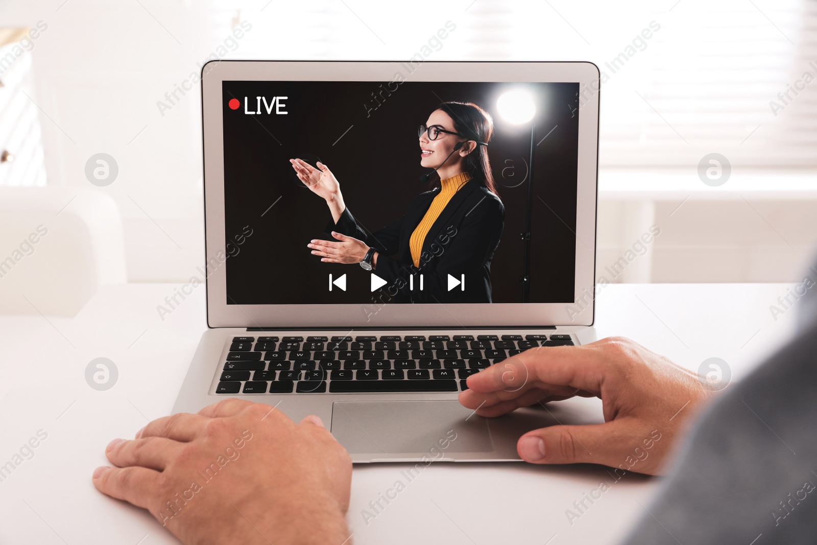 Image of Man watching performance of motivational speaker on laptop at white table, closeup