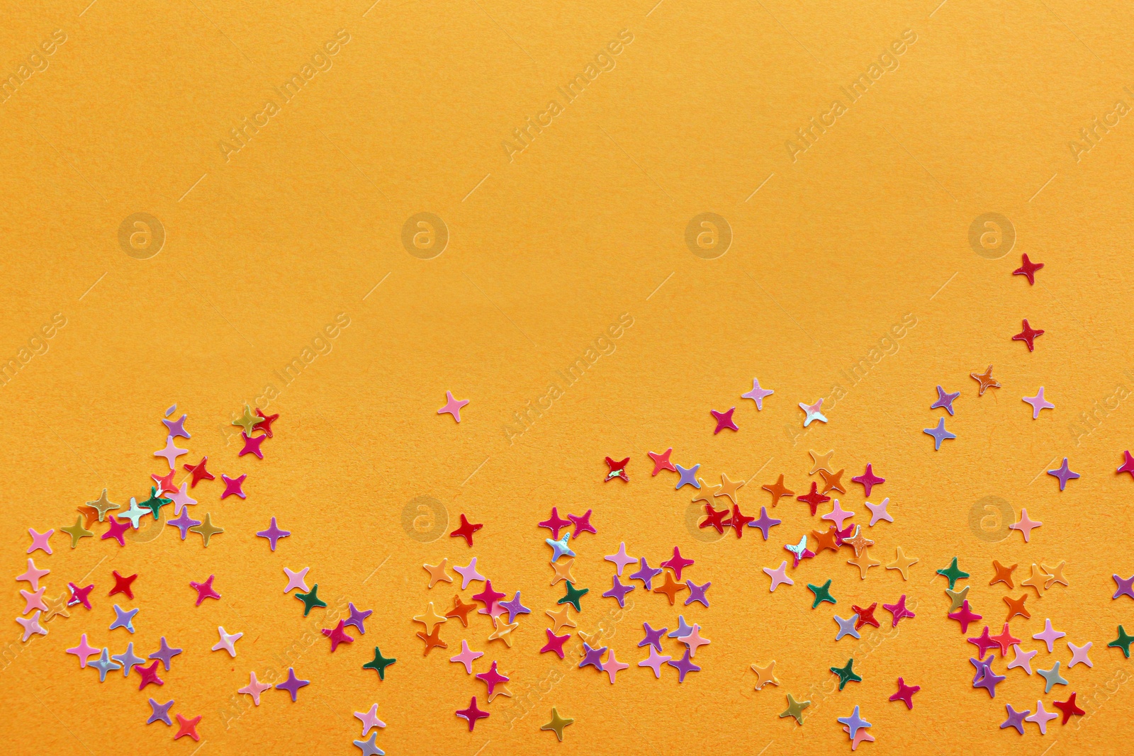 Photo of Shiny bright colorful glitter on pale orange background, top view. Space for text