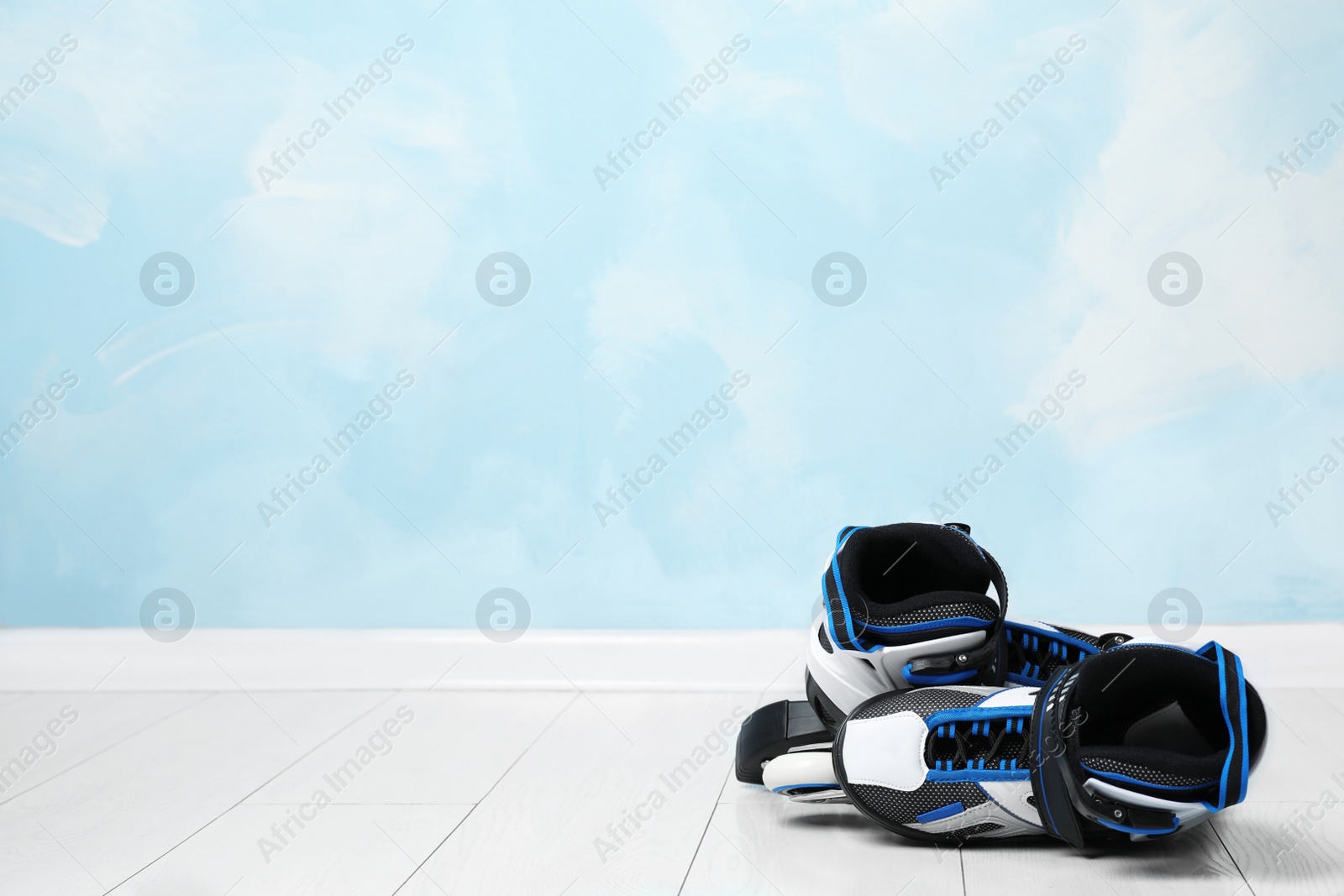 Photo of Inline roller skates on floor near color wall. Space for text