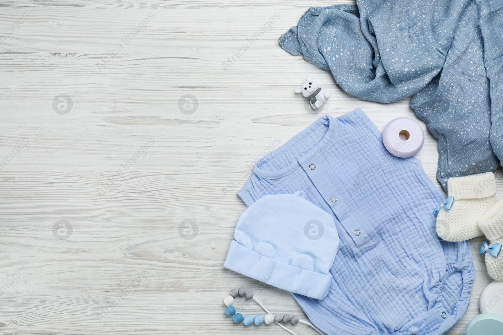 Photo of Flat lay composition with baby clothes and accessories on white wooden table. Space for text