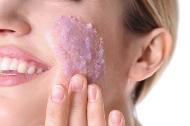 Photo of Young woman applying natural scrub on her face against white background, closeup