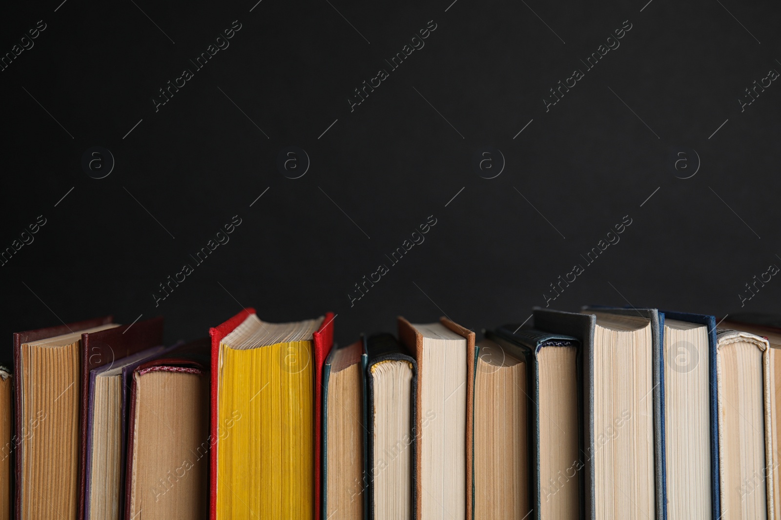 Photo of Stack of hardcover books on black background. Space for text