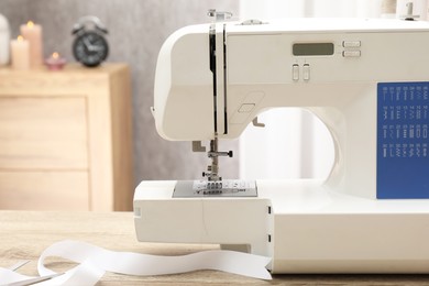 Photo of White sewing machine on wooden table indoors