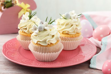 Photo of Tasty Easter cupcakes with vanilla cream on wooden table