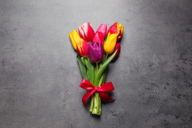 Photo of Beautiful spring tulips on grey stone table, top view