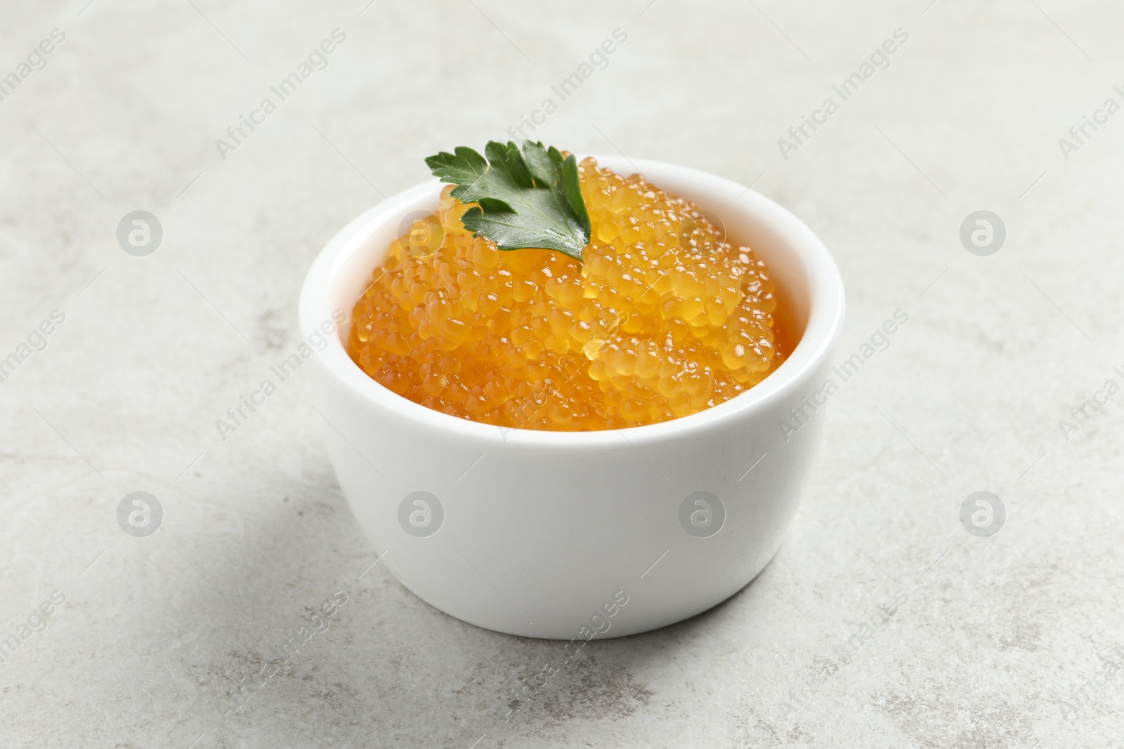 Photo of Fresh pike caviar and parsley in bowl on light grey table