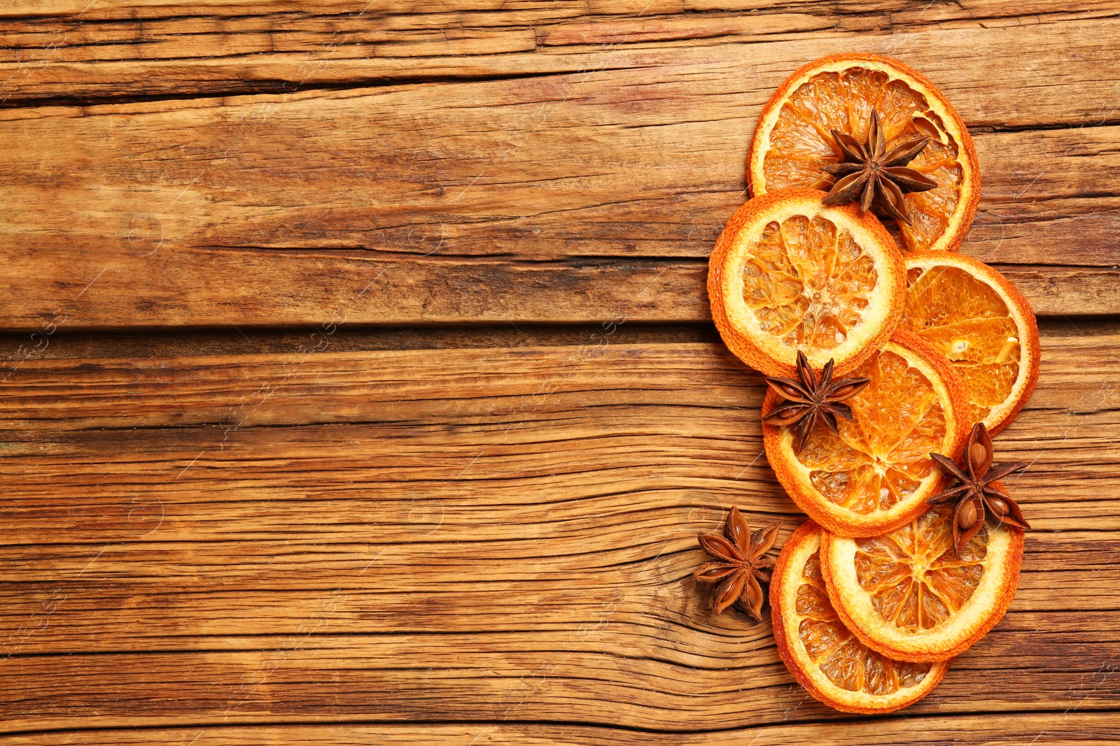 Photo of Dry orange slices and anise stars on wooden table, flat lay with space for text