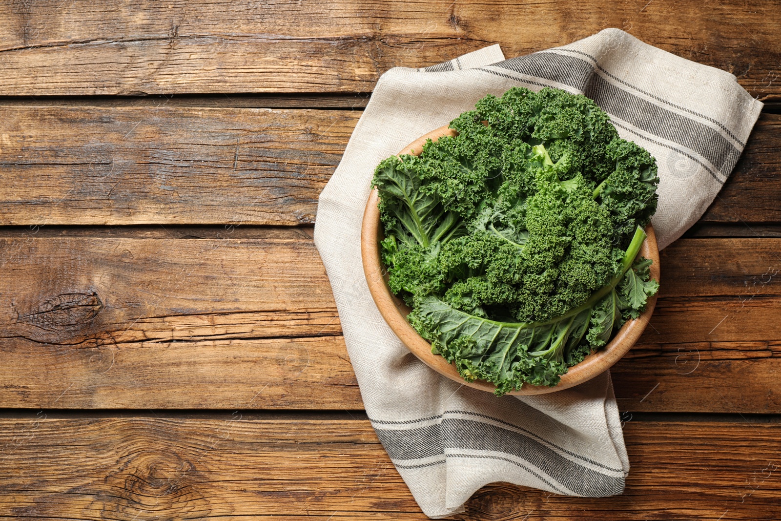 Photo of Fresh kale leaves on wooden table, top view. Space for text