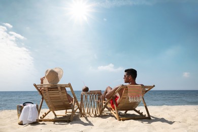 Photo of Couple resting in wooden sunbeds on tropical beach