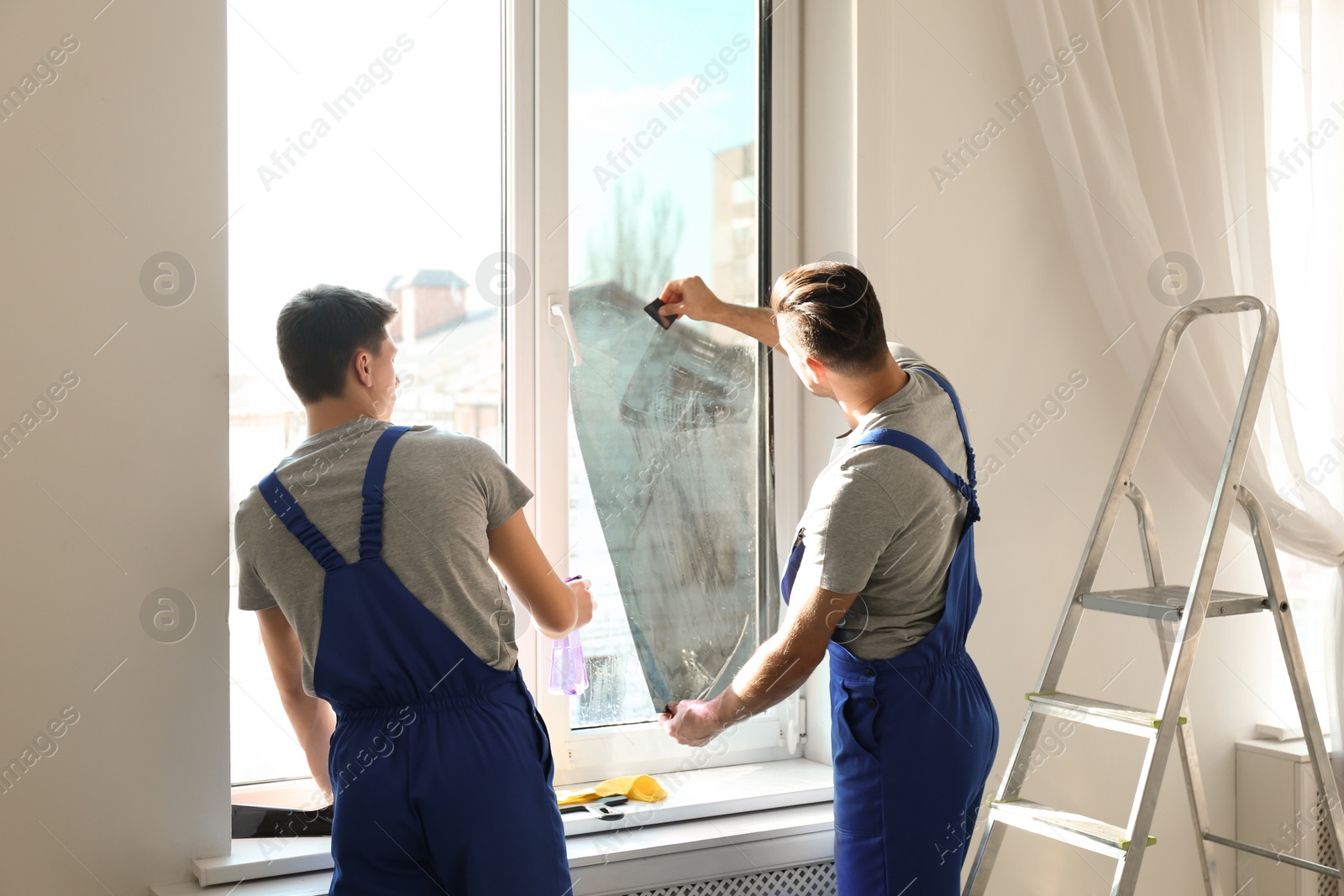 Photo of Professional workers tinting window with foil indoors