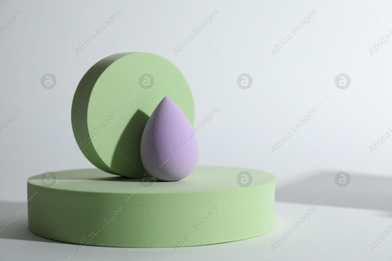 Photo of Stylish presentation of violet makeup sponge on white background, space for text