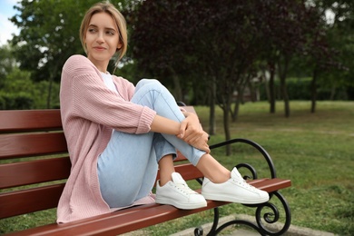 Photo of Beautiful young woman sitting on bench in park