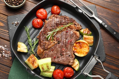 Photo of Delicious grilled beef steak and vegetables served on wooden table, top view
