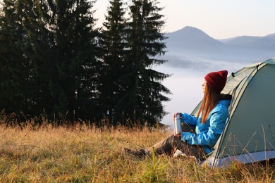 Photo of Woman near camping tent surrounded by beautiful nature. Space for text