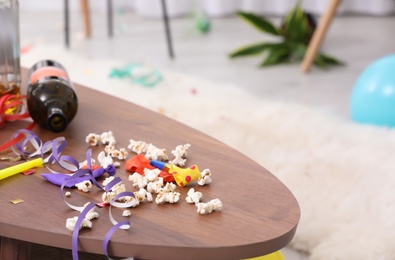 Photo of Messy table with popcorn, streamers and bottle after party indoors