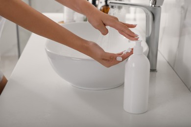 Teenage girl using gel in bathroom, closeup. Skin care cosmetic