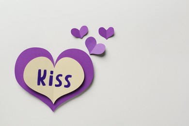 Photo of Paper hearts and one with word Kiss on beige background, flat lay. Space for text