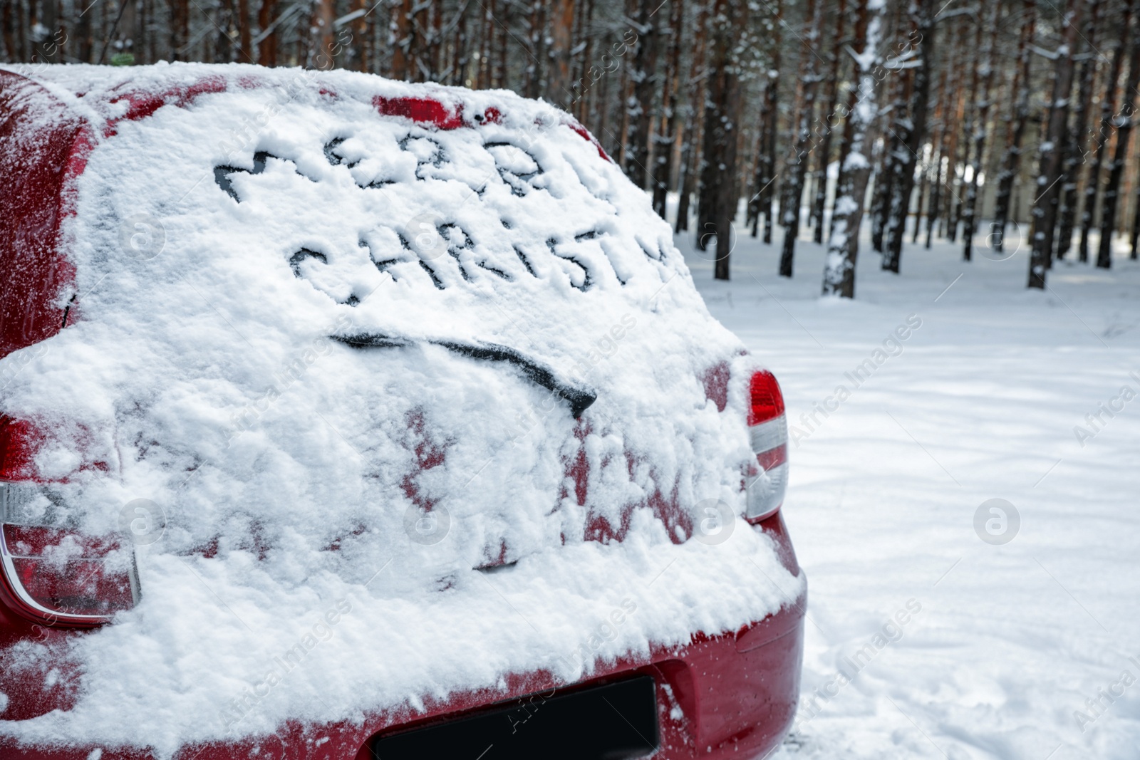 Photo of Phrase "Merry Christmas" written on snow covered car in winter forest. Space for text