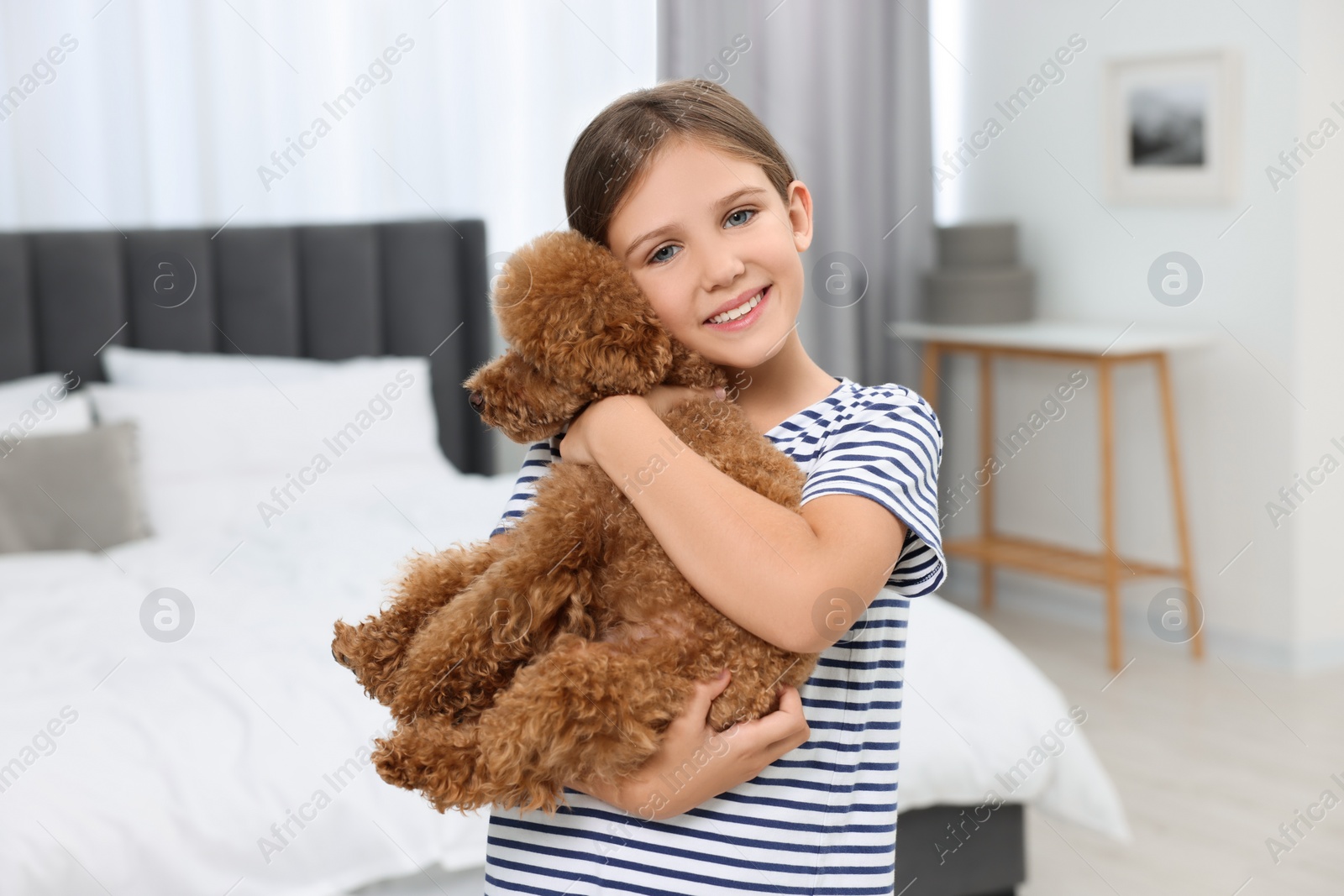 Photo of Little child with cute puppy in bedroom. Lovely pet