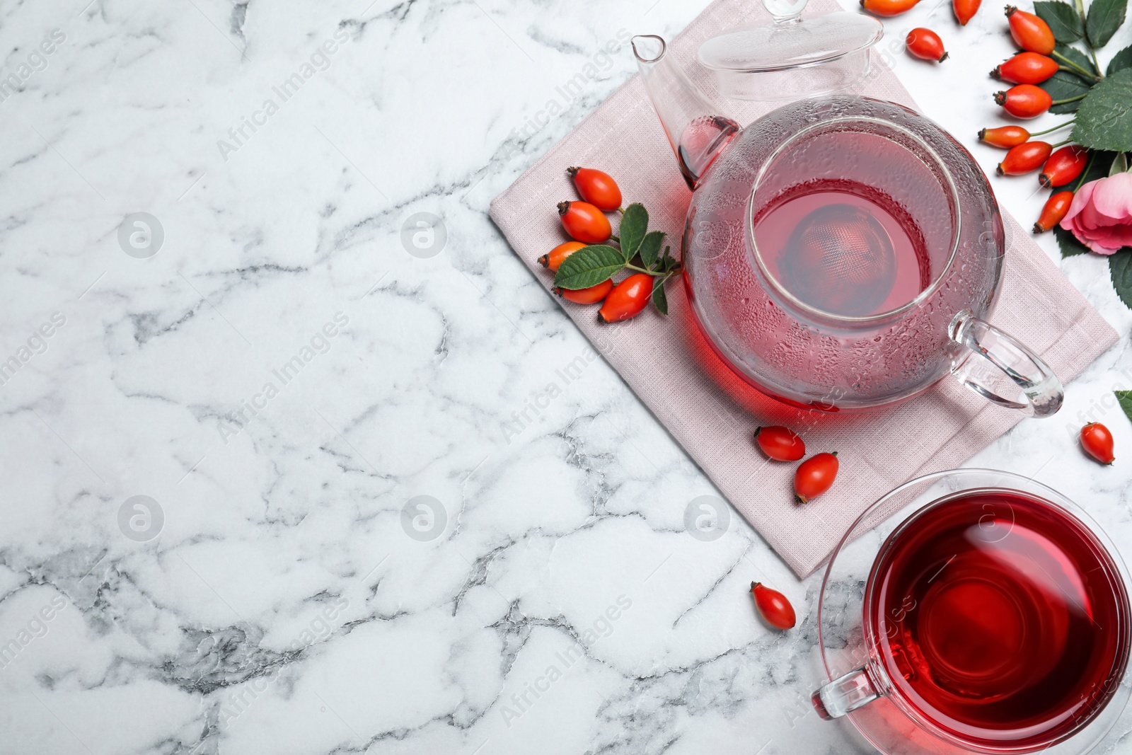 Photo of Fresh rose hip tea and berries on white marble table, flat lay. Space for text