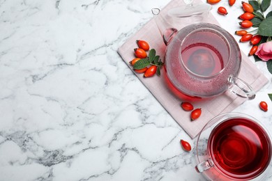 Photo of Fresh rose hip tea and berries on white marble table, flat lay. Space for text