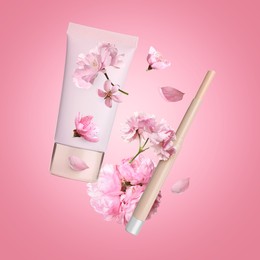 Spring flowers and makeup products in air on pink background