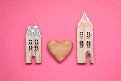 Photo of Long-distance relationship concept. Decorative heart between two house models on pink background, flat lay