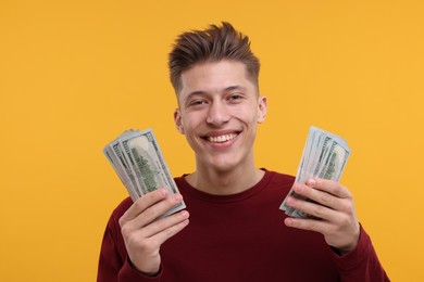 Photo of Happy man with dollar banknotes on yellow background