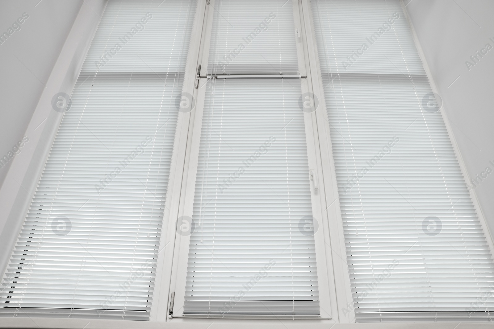 Photo of Stylish window with horizontal blinds in room, low angle view