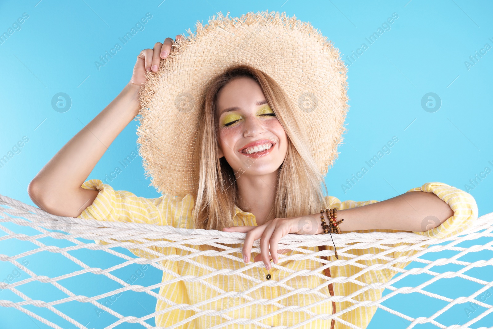 Photo of Beautiful young woman posing near net on color background. Summer fashion