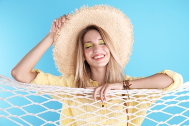 Beautiful young woman posing near net on color background. Summer fashion