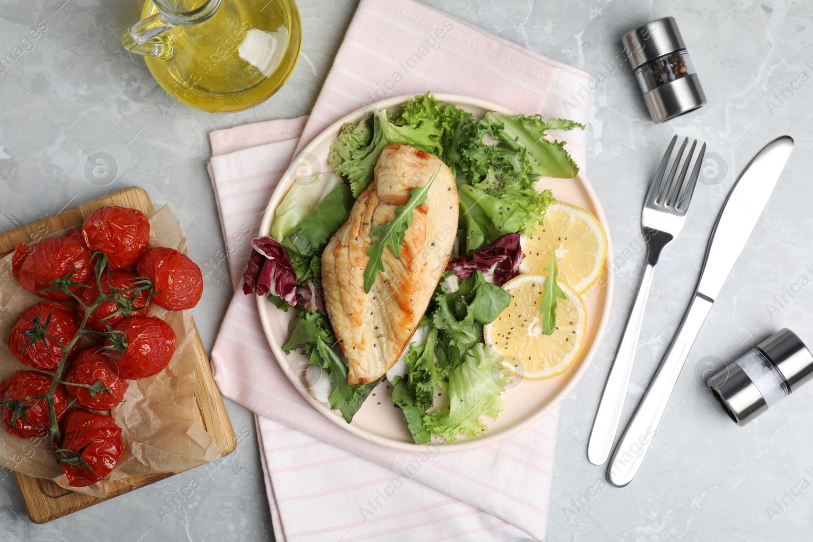 Photo of Delicious cooked chicken and fresh salad served on grey marble table, flat lay. Healthy meals from air fryer