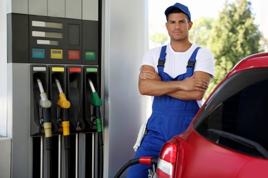 Photo of Worker refueling car at modern gas station