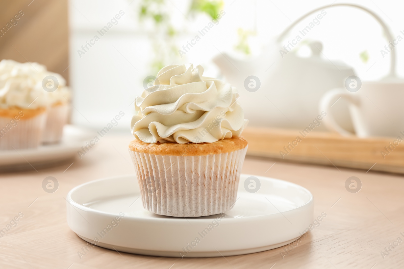 Photo of Tasty cupcake with vanilla cream on light wooden table, closeup