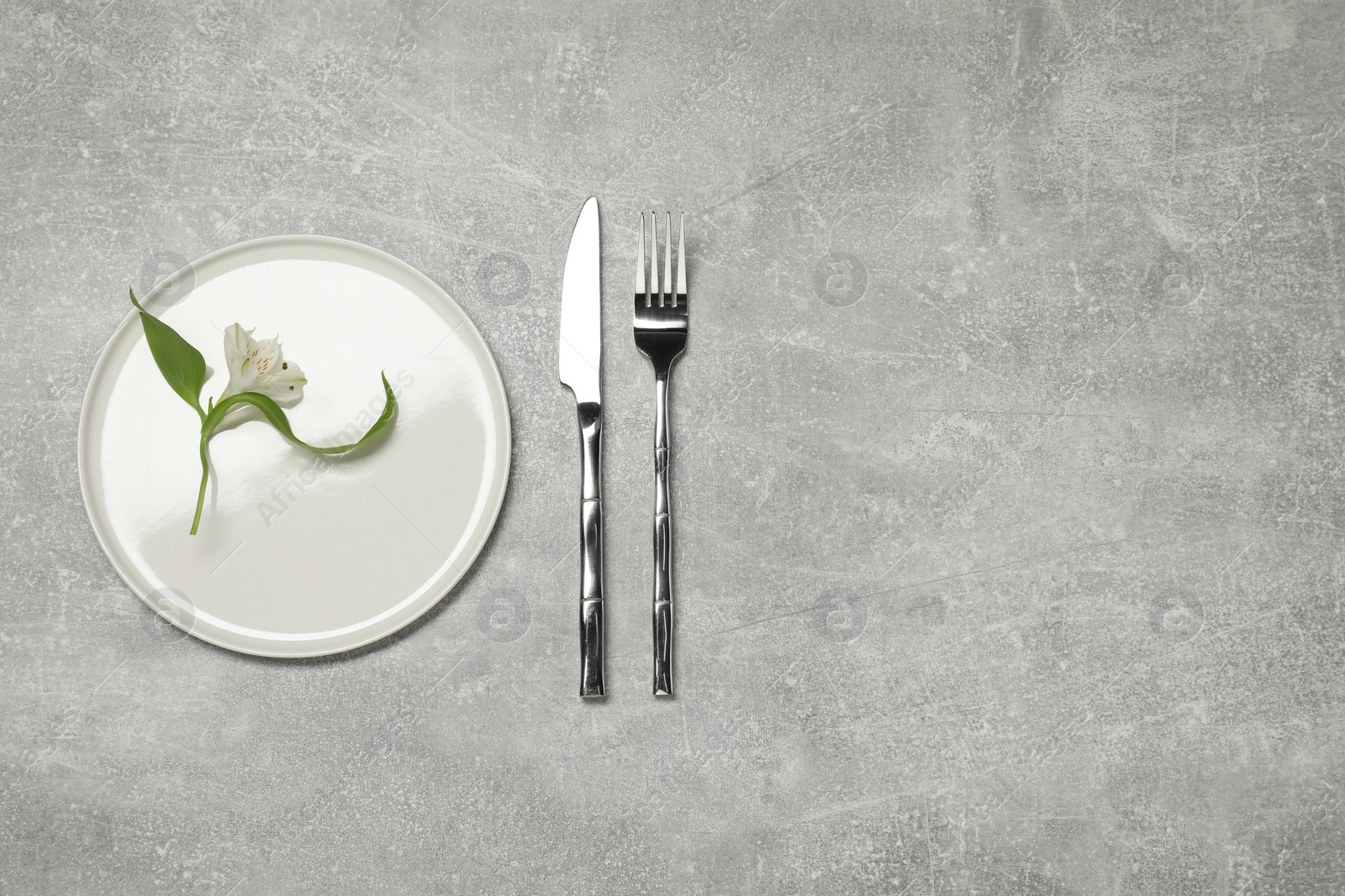 Photo of Setting with beautiful cutlery on grey textured table, top view. Space for text