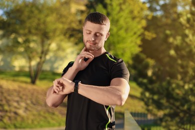 Photo of Attractive man checking pulse after training in park