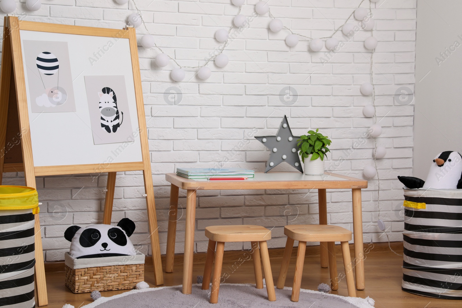Photo of Stylish child room interior with wooden table and board near white brick wall