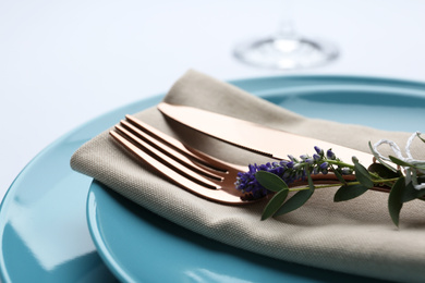 Photo of Stylish elegant cutlery with napkin and floral decor in plate on white background, closeup
