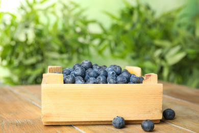 Tasty ripe blueberries in crate on wooden table