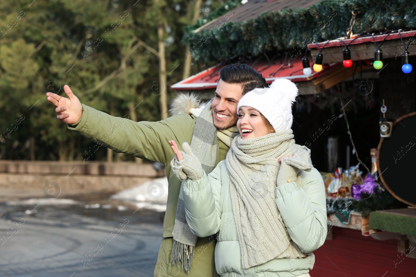 Photo of Happy couple in warm clothes at winter fair. Christmas season