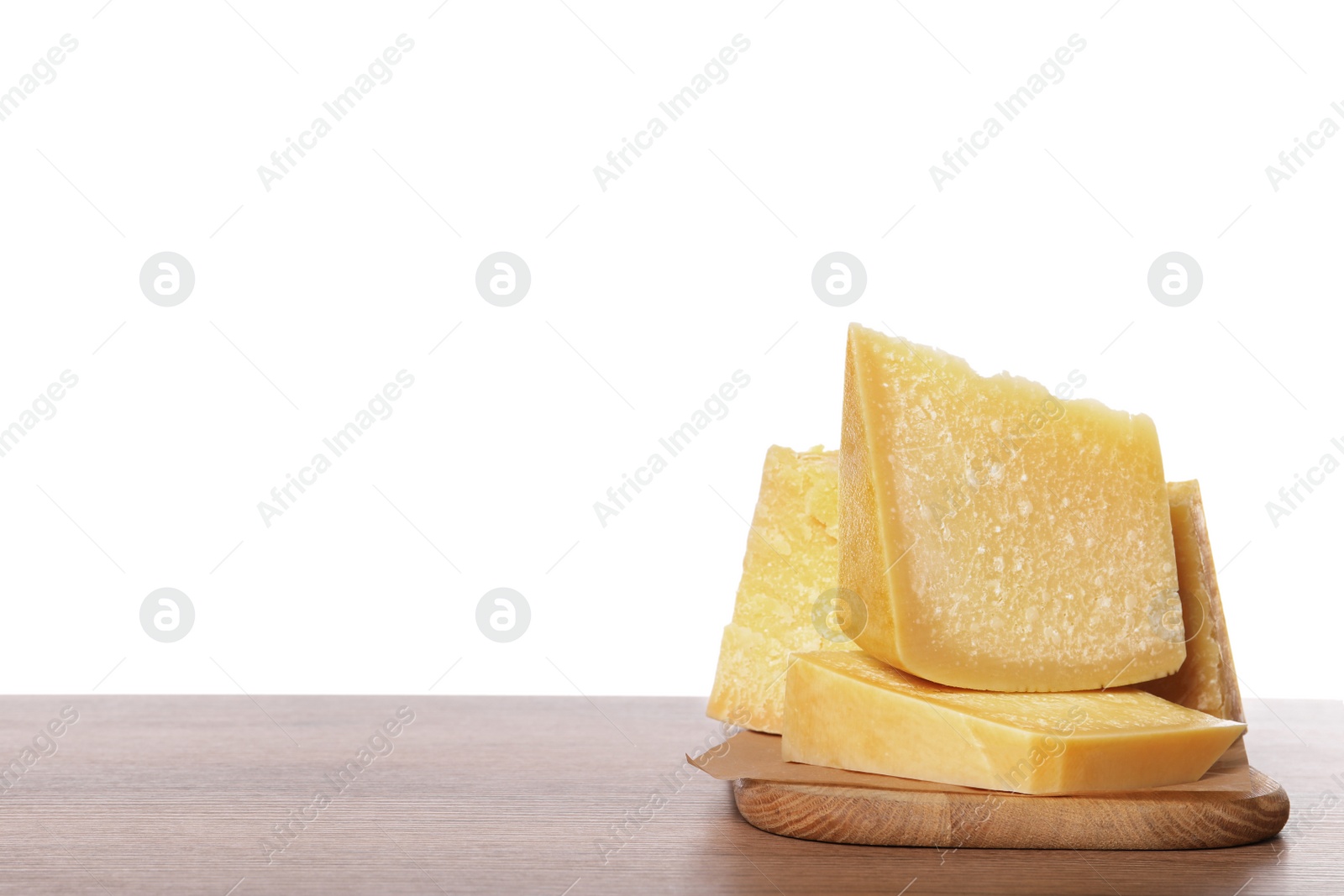 Photo of Pieces of delicious parmesan cheese on wooden table against white background. Space for text