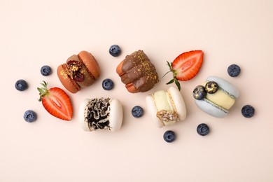 Delicious macarons and berries on beige table, flat lay