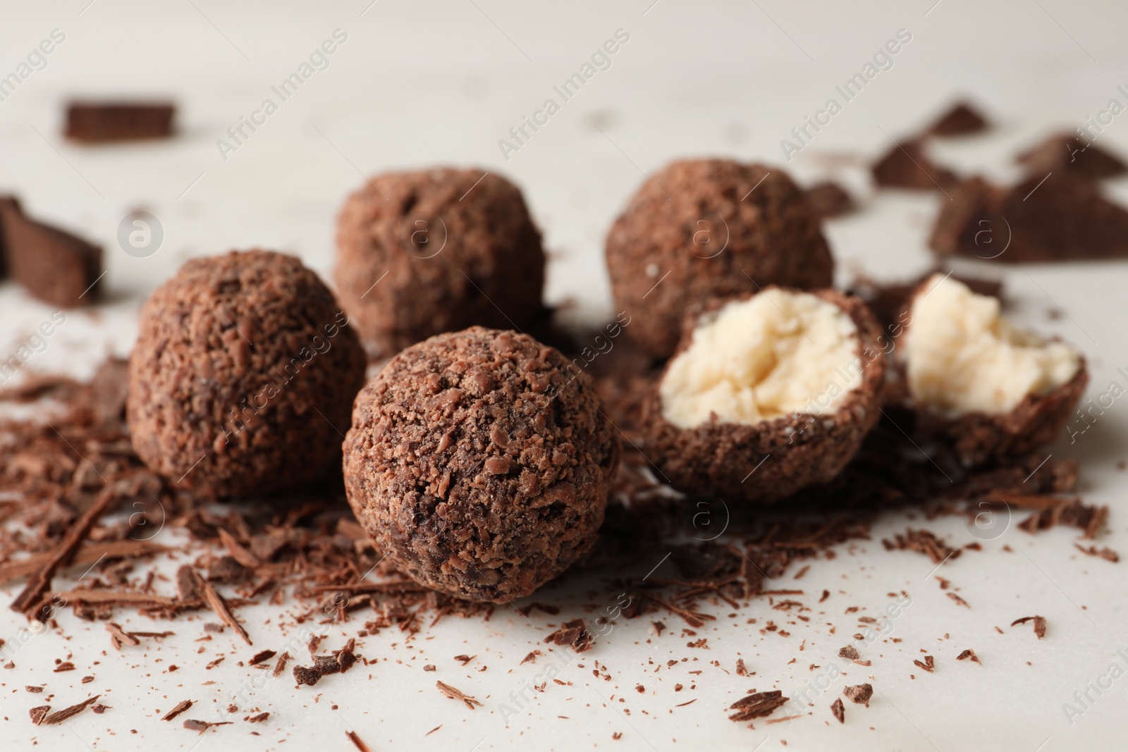 Photo of Many delicious chocolate truffles on light table, closeup