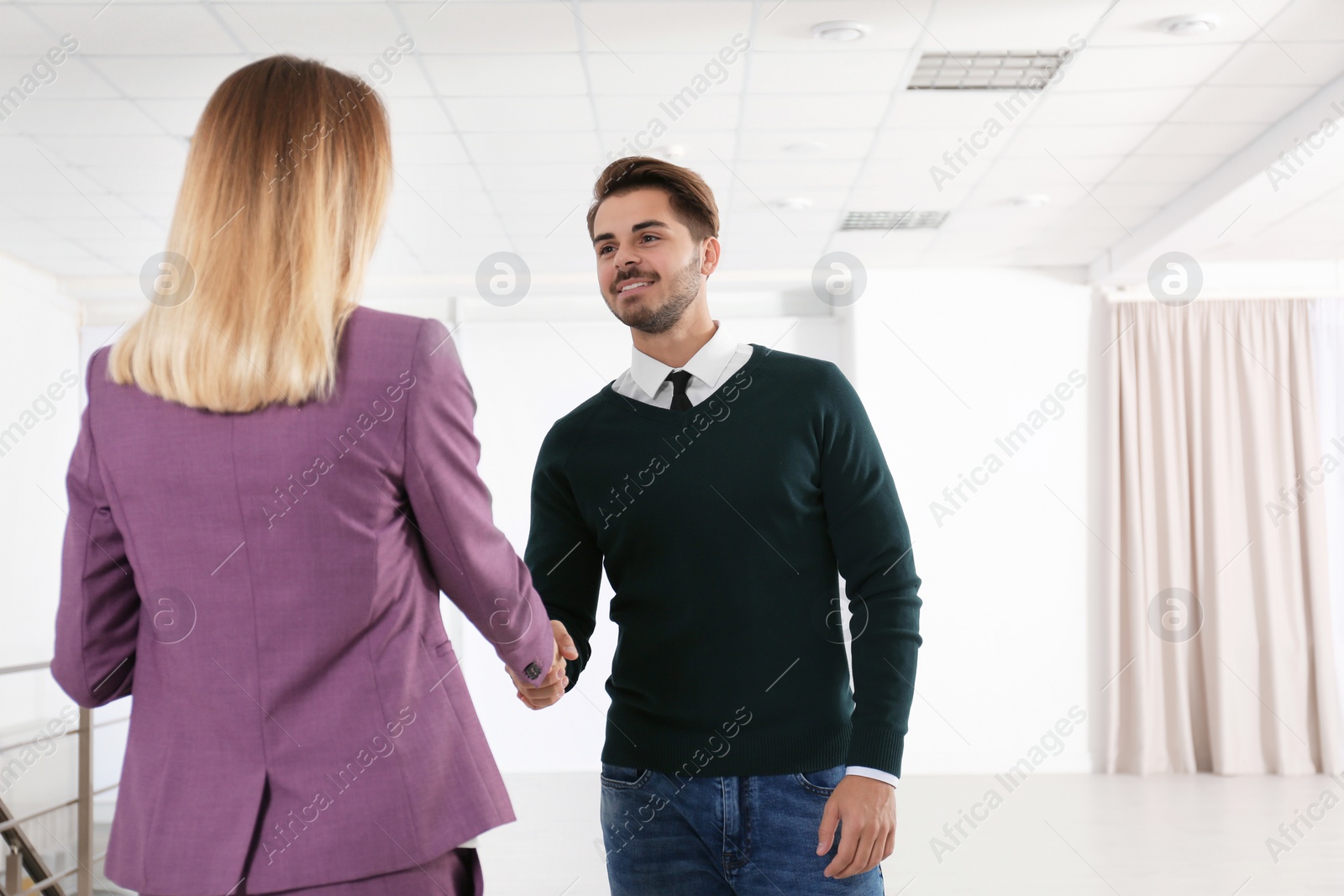 Photo of Real estate agent shaking hands with client in new apartment. Space for text